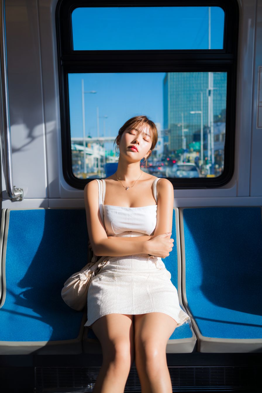 若い韓国の女性が地下鉄で静かに眠っている、白いトップスとミニスカートを着ている