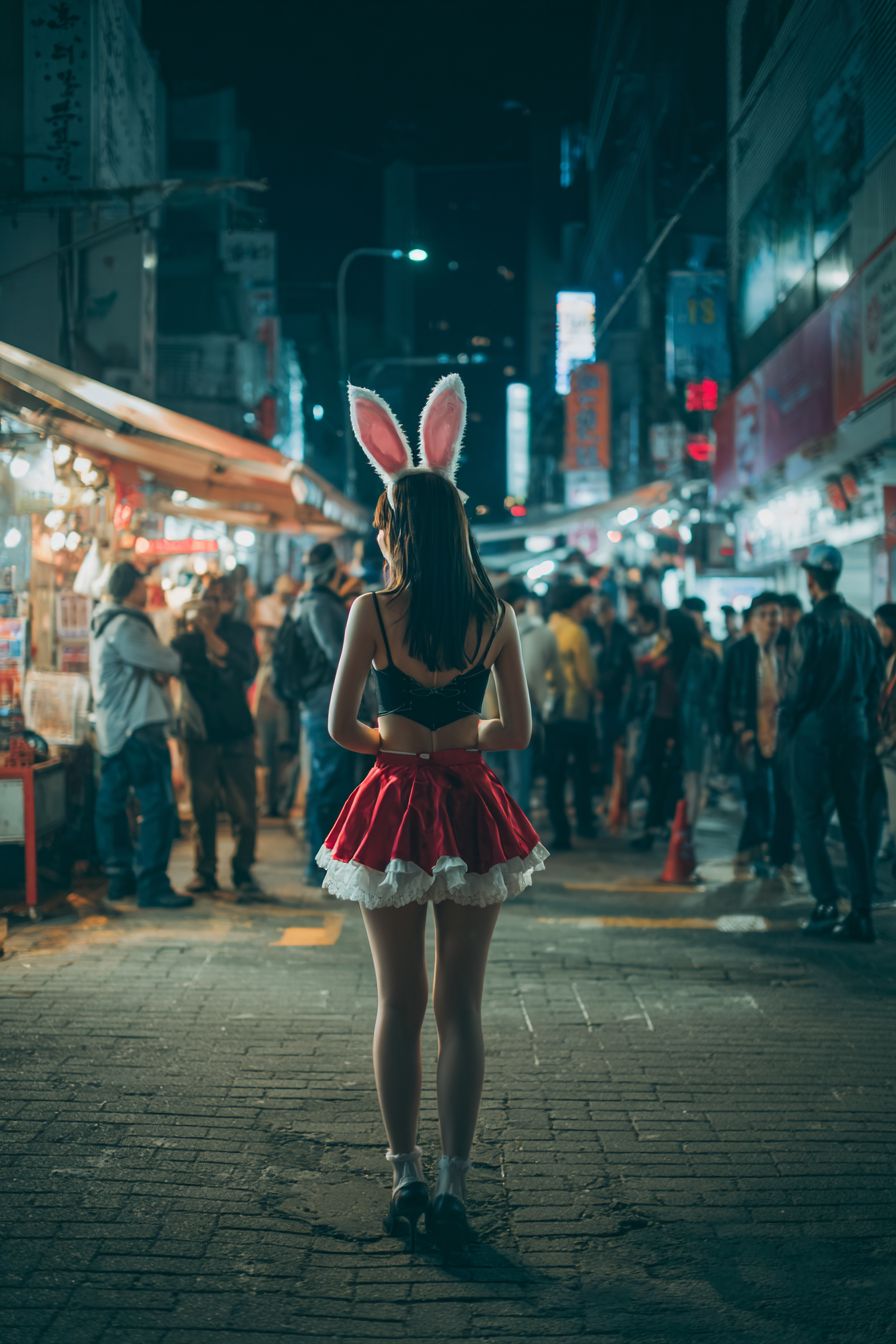 Una mujer asiática con un disfraz de conejo está en las calles por la noche