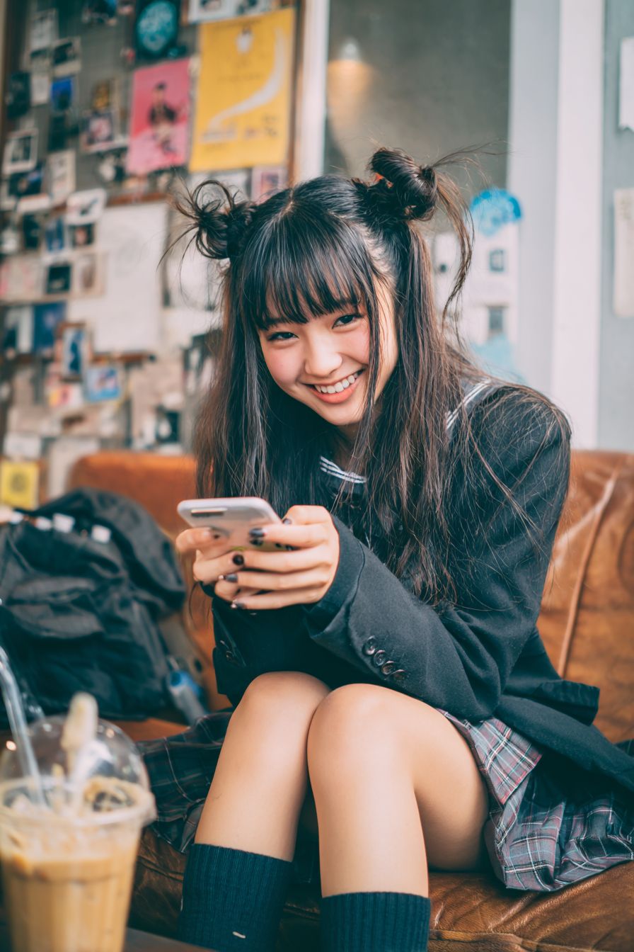 一位美麗的日本高中女孩正坐在咖啡店的沙發上