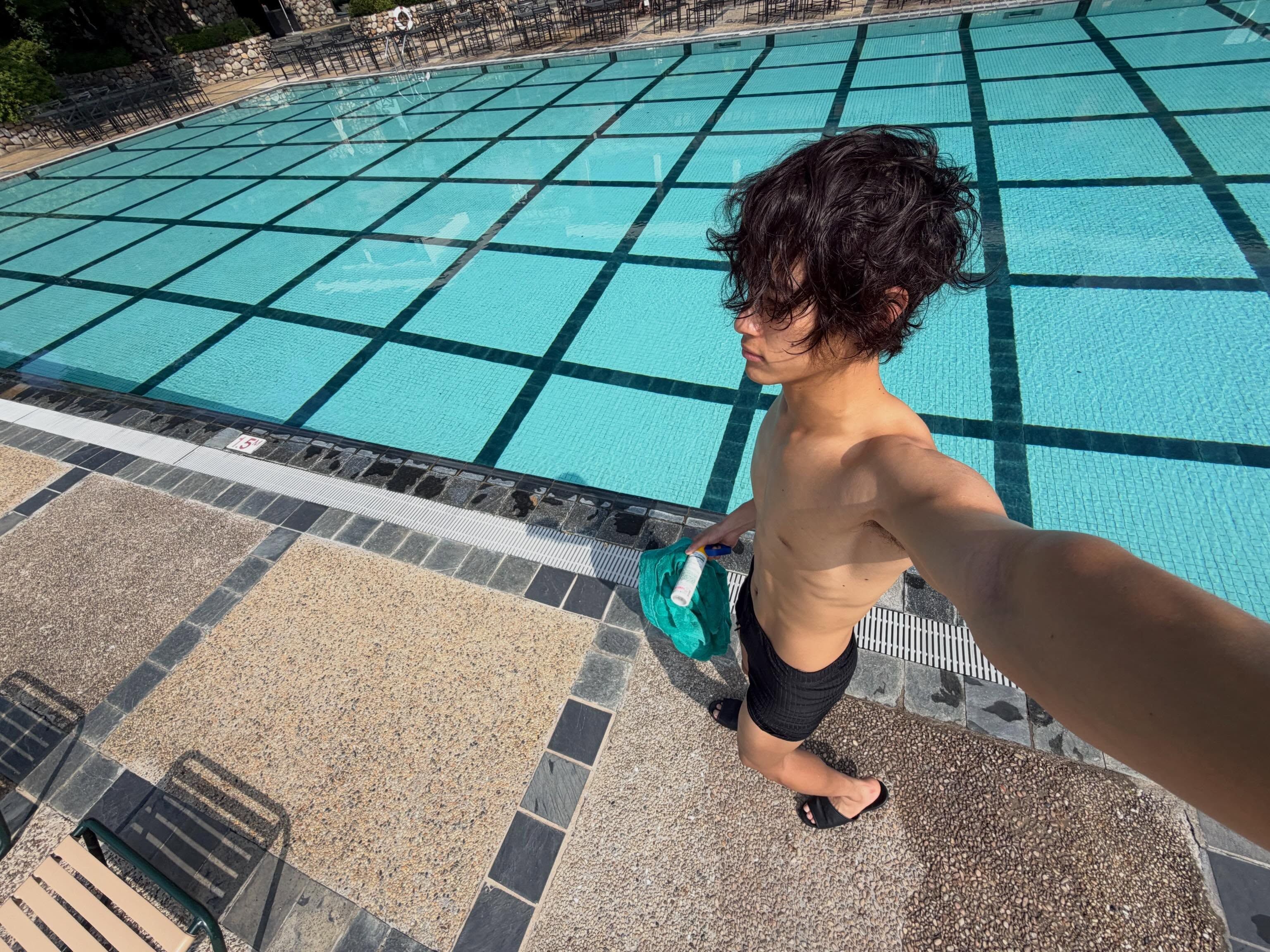 年輕男子在戶外游泳池邊赤膊穿黑色泳褲自拍