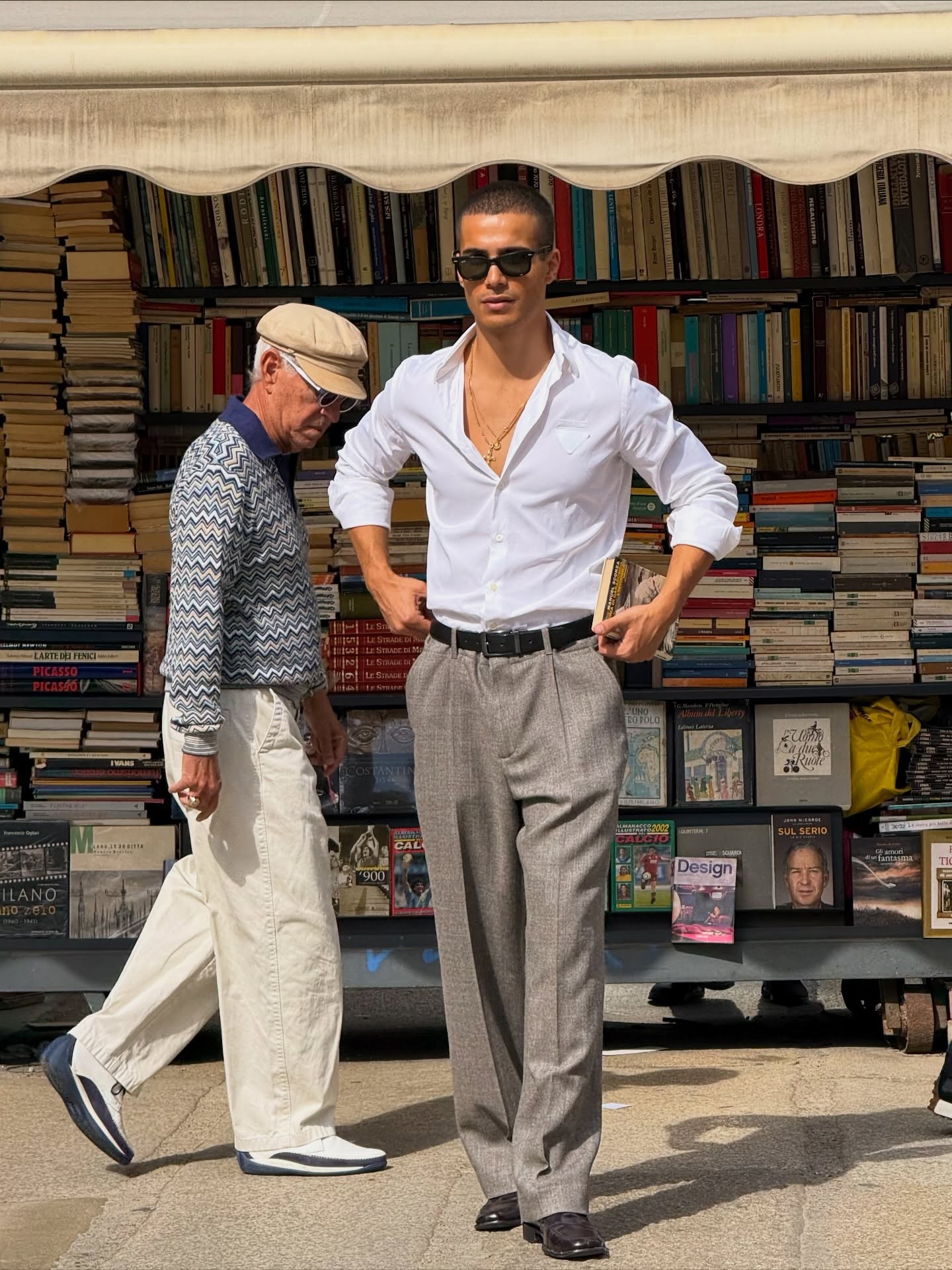 Ein junger Mann liest ein Buch in weißem Hemd und grauer Hose auf einem Outdoor-Büchermarkt